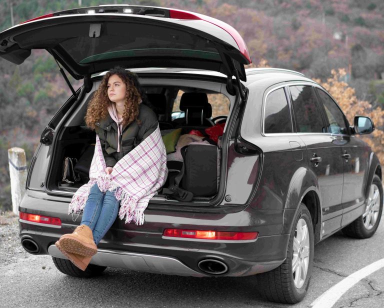 full-shot-woman-sitting-car-trunk (1)